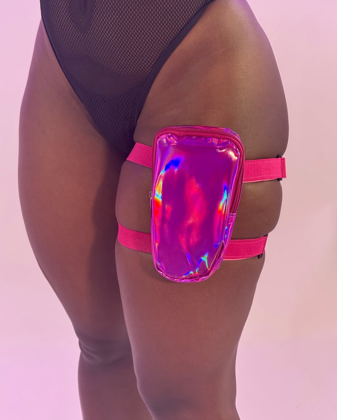 Holographic thigh bag worn by a person on a pink background